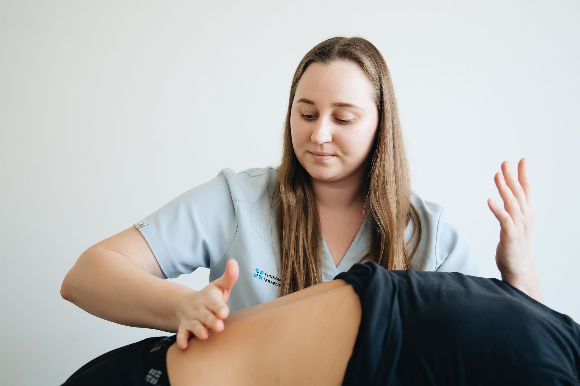 Una fisioterapeuta trabaja la espalda de un paciente en una sala clara
